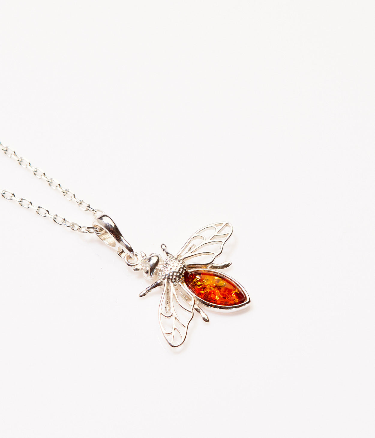 Silver bee pendant with amber body on a white background