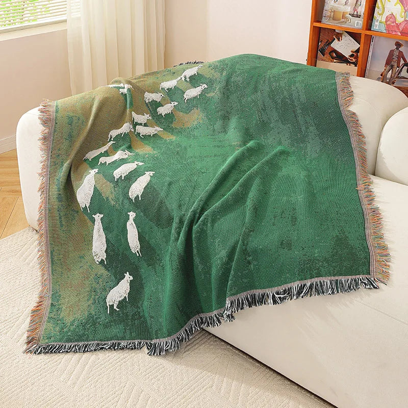 Green blanket with white animal pattern draped over a white couch in a living room.